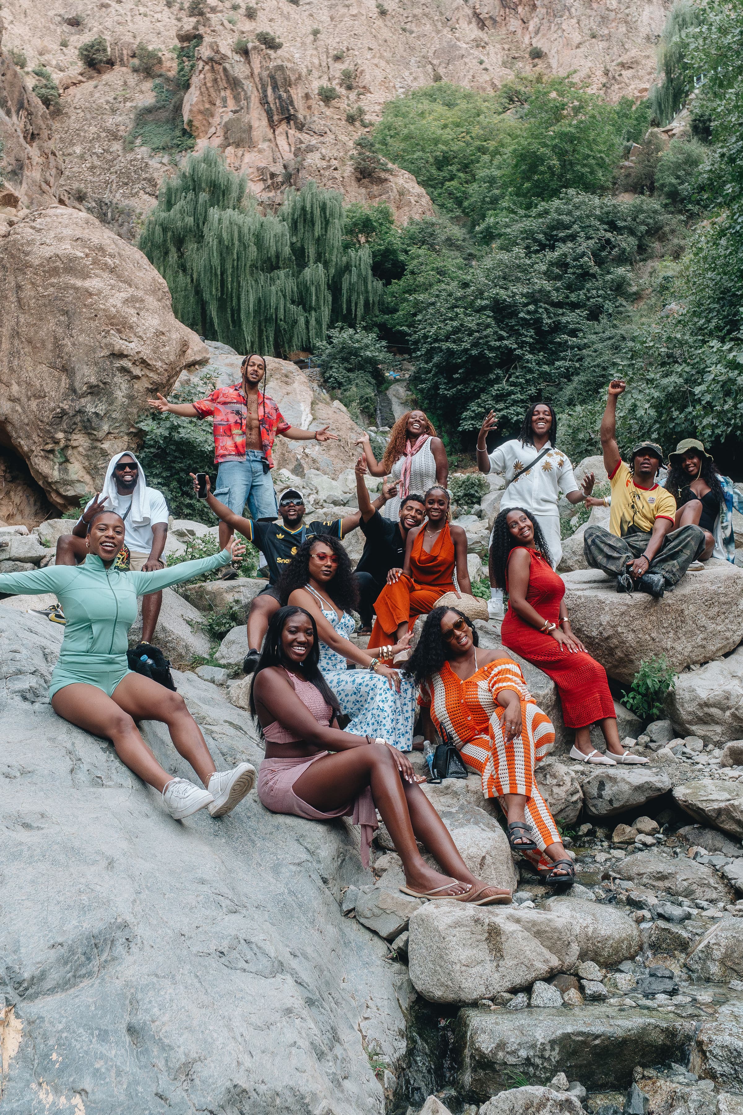 A group of Black friends posing on large rocks in a scenic, mountainous canyon.